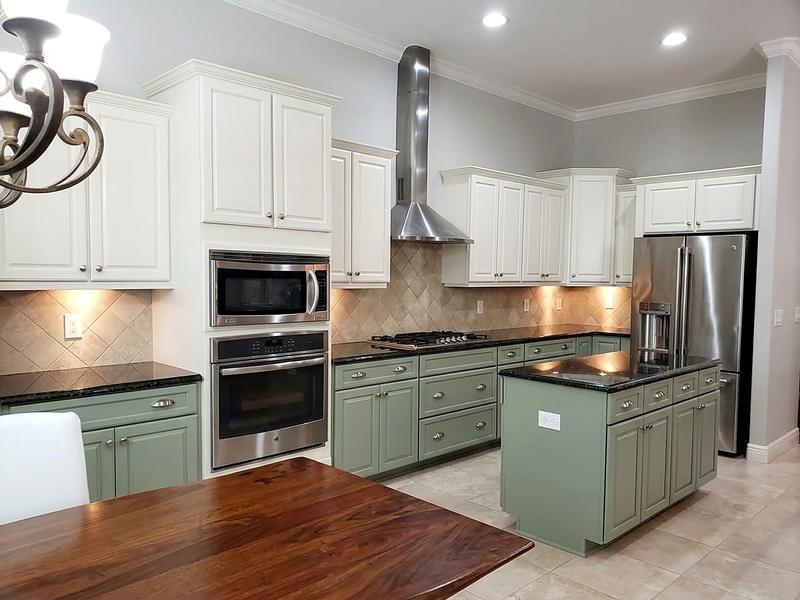 After: the same kitchen with white upper cabinets and sage green lower cabinets and island